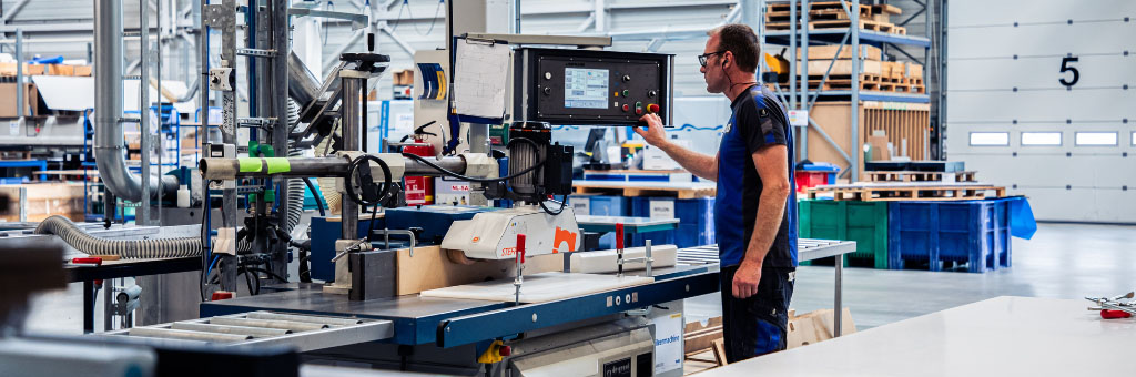 Ein Mitarbeiter bedient eine Industriemaschine in einer Produktionshalle.