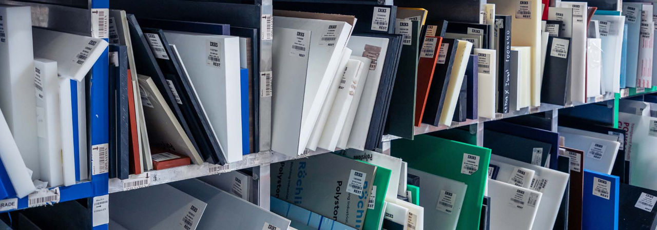 Eine Nahaufnahme von Regalen, die mit ordentlich geordneten Kunststoffmustern in verschiedenen Farben und Größen gefüllt sind, die jeweils mit ERIKS Produktetiketten versehen sind.
