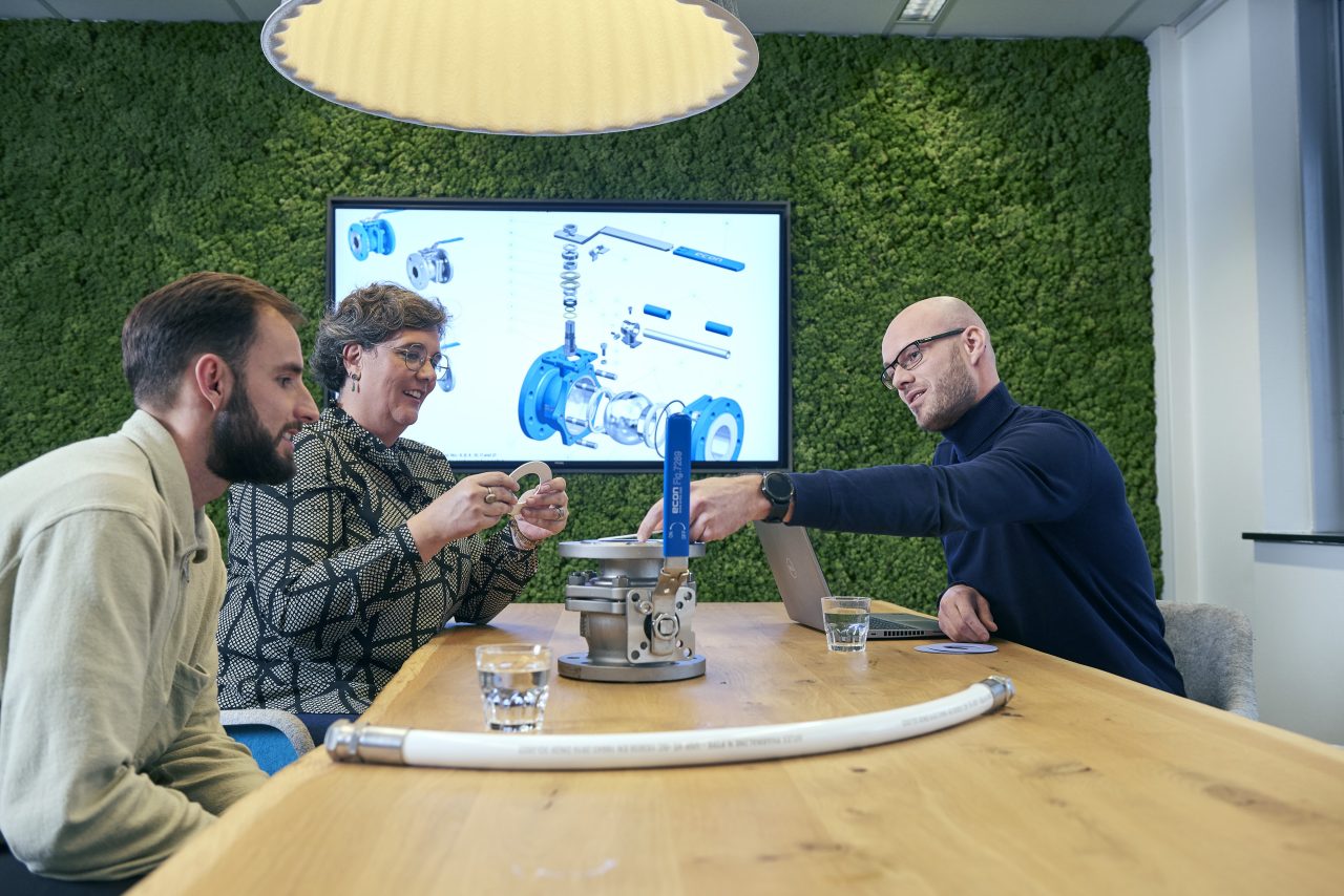  Vier Personen besprechen ein technisches Modell am Konferenztisch.