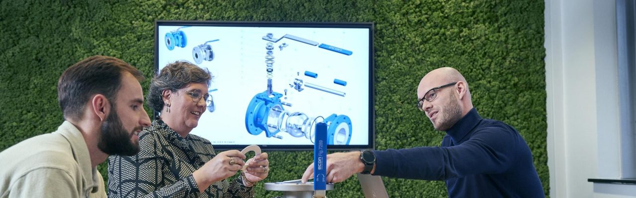 Drei Personen besprechen ein technisches Modell am Konferenztisch